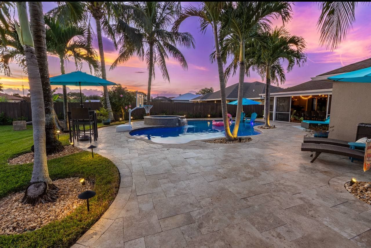 Resort-style pool with palm trees at purple sunset